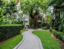 Curved pathway leading to a modern apartment building surrounded by lush greenery