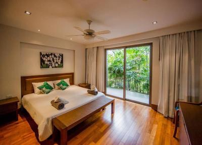 Spacious bedroom with large windows and lush greenery view