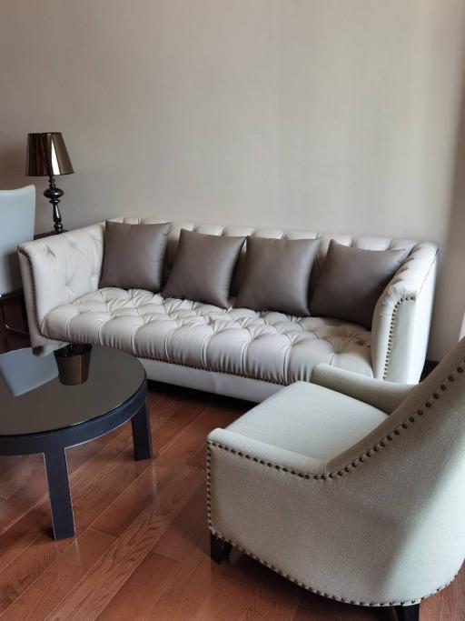 Elegant living room with a tufted sofa, round coffee table, and a classic lamp