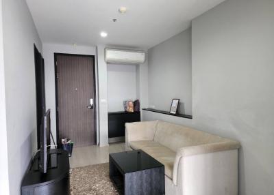 Modern living room interior with beige sofa, textured rug, and air conditioning unit