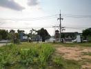 Empty plot of land with utility poles and wires against a clear sky