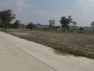 Suburban development area with empty plots and new housing in the background