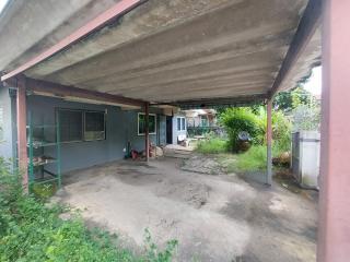 Spacious carport area with concrete flooring leading to a house entrance