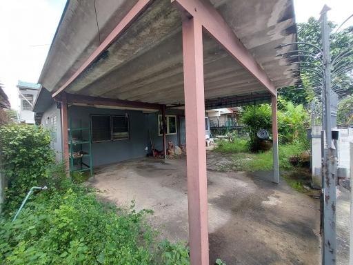 Spacious outdoor area with a covered carport, adjacent to a residential building