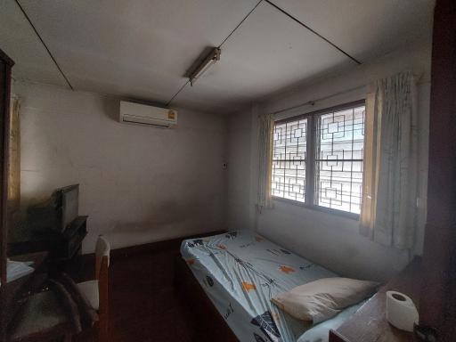 Sparse bedroom with a single bed, window, and an air conditioning unit