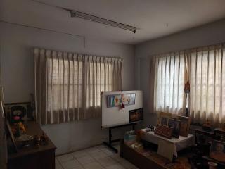 Spacious living room with natural lighting and tiled floors, featuring a whiteboard, curtains, and decorative items