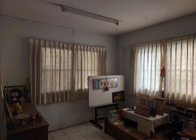 Spacious living room with natural lighting and tiled floors, featuring a whiteboard, curtains, and decorative items