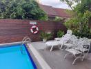 Cozy outdoor pool space with lounging chairs and privacy fencing