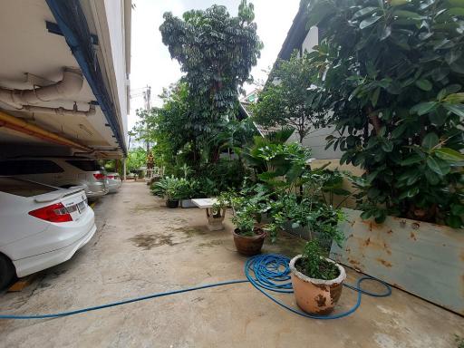 Paved exterior area of a property with parked cars and potted plants