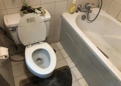 A bathroom with toilet and bathtub showing signs of use
