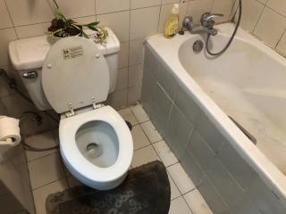 A bathroom with toilet and bathtub showing signs of use