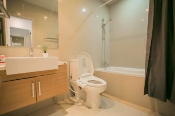 Modern bathroom with toilet, bathtub, and vanity