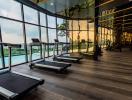 Modern gym with treadmills overlooking city view through floor-to-ceiling windows