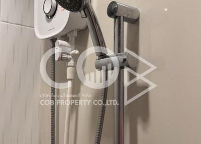 Modern wall-mounted electric shower unit with adjustable shower head in a tiled bathroom