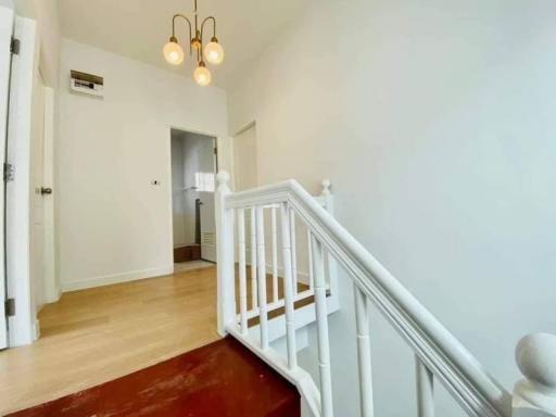 Bright hallway with wooden flooring and white balustrade