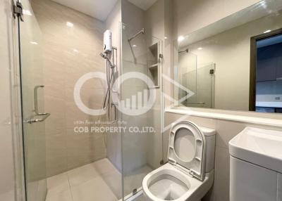 Modern bathroom with glass shower cubicle, ceramic toilet, and neutral color tiles