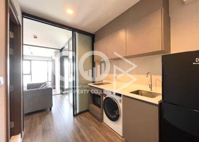 Compact apartment interior with integrated kitchen, living space, and laundry