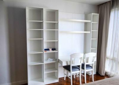 Bright bedroom with large bed, bookshelves, and dining area