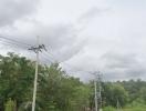 Cloudy sky over green landscape with power lines