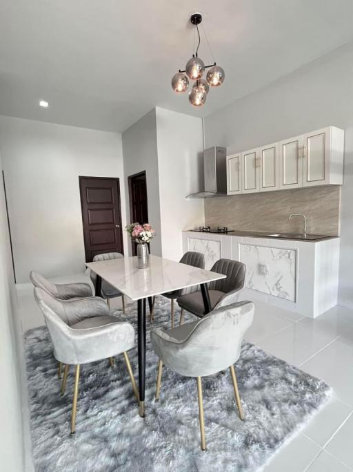 Modern kitchen with dining area featuring elegant table and chairs, stylish cabinetry, and chic lighting