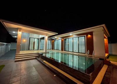 Modern home exterior at night with illuminated facade and swimming pool