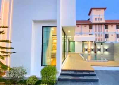 Modern white building exterior at dusk with illuminated interior and landscaping