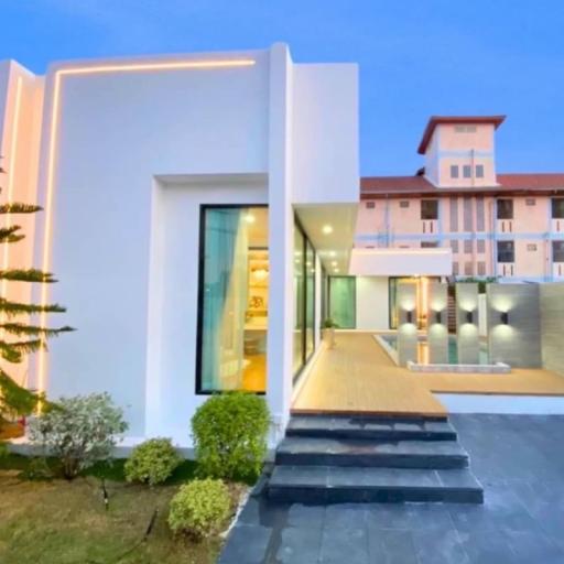 Modern white building exterior at dusk with illuminated interior and landscaping