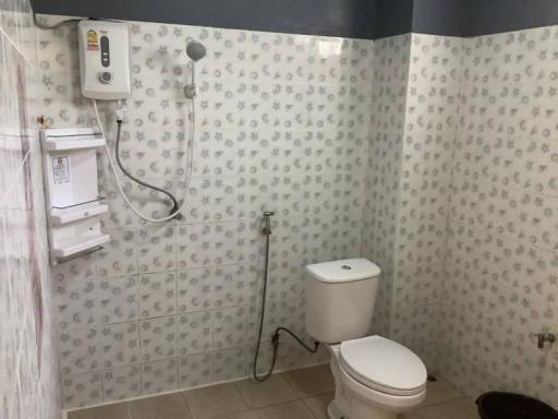 Bathroom with white fixtures, shower, and patterned tile walls