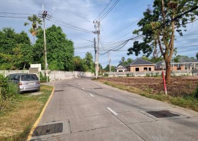 Paved street with residential land and buildings under a clear blue sky