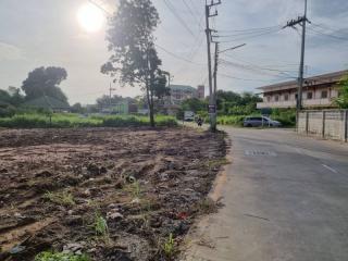 Empty land plot near a road with residential buildings in the background