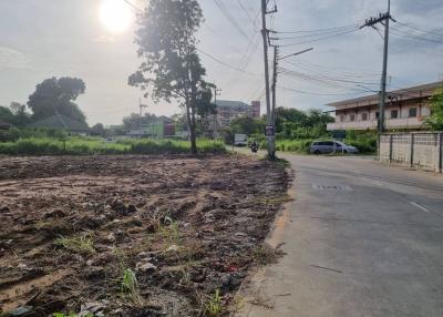 Empty land plot near a road with residential buildings in the background