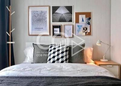 Cozy bedroom interior with a neatly made bed, framed artwork, and soft lighting
