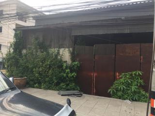 Exterior view of a rustic building with visible wear and overgrown foliage