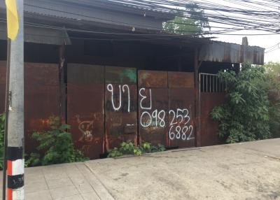 Rusty gate of a building with overgrown foliage and contact numbers