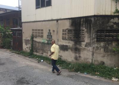 Exterior view of a building showing signs of wear and a person walking by