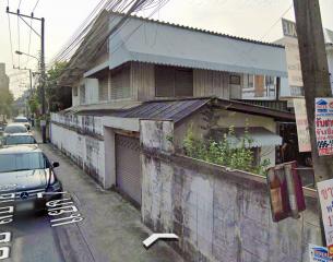 Exterior view of a two-story building with overgrown plants