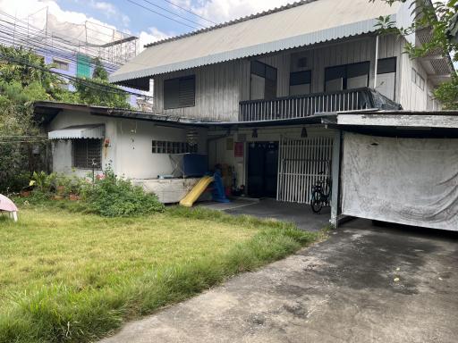 Front view of a two-story residential house with lawn and outdoor items