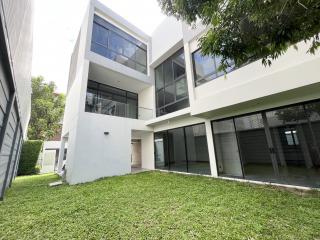 Modern two-story house with large windows and spacious lawn