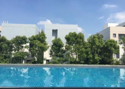 Sparkling outdoor swimming pool with modern buildings and lush greenery in the background