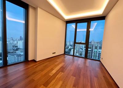 Spacious living room with hardwood floors and large windows offering a city view