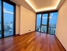 Spacious living room with hardwood floors and large windows offering a city view