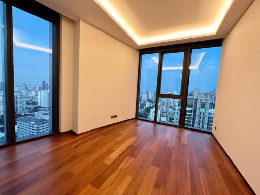 Spacious living room with hardwood floors and large windows offering a city view