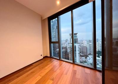 Spacious bedroom with large windows and city skyline view