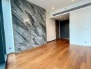 Empty interior space of a building with hardwood floors and a large accent marble wall