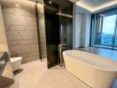 Spacious modern bathroom with freestanding tub, large shower, and city views