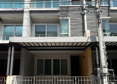 Modern three-story residential building with balcony and gated entrance
