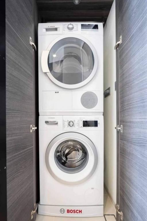 Stacked white Bosch washing machine and dryer in a modern laundry room