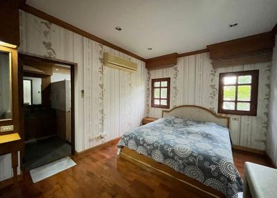 Cozy bedroom with wooden flooring and patterned wallpaper