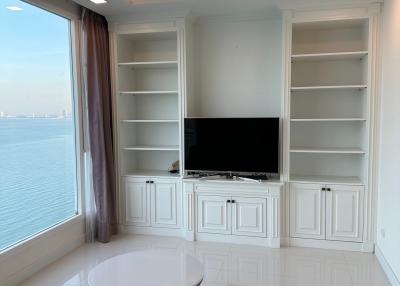 Modern living room with ocean view, featuring white built-in cabinets and porcelain tile flooring