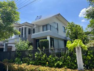 Modern two-story house with a balcony and lush greenery